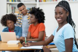 4 African-American teens working on summer projects while one of the girls smiles at the camera